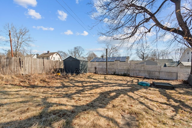 view of yard featuring a fenced backyard, a storage unit, and an outdoor structure