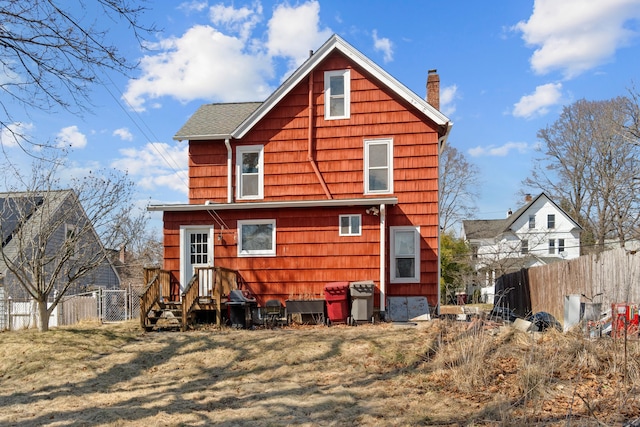 back of property featuring a lawn, a chimney, and fence