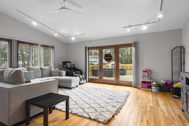 living area featuring vaulted ceiling, light wood-style floors, a wealth of natural light, and ceiling fan