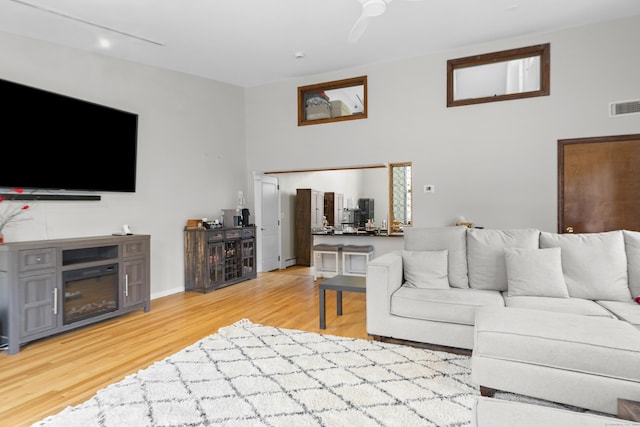 living room with visible vents, light wood-style flooring, and a ceiling fan