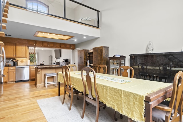 dining area with light wood-style floors and a towering ceiling