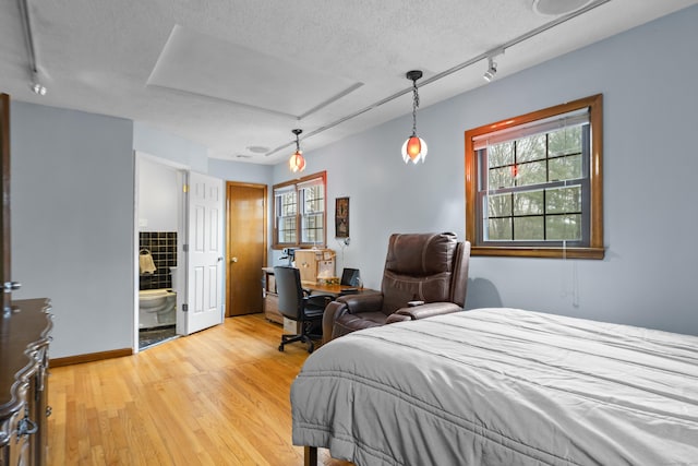 bedroom featuring multiple windows, a textured ceiling, and light wood-style flooring