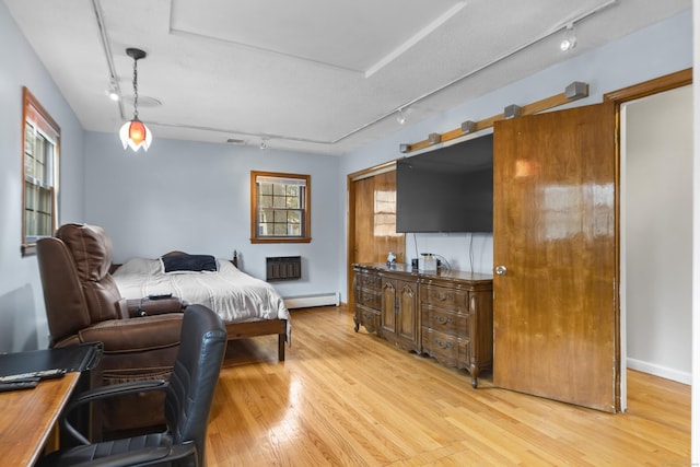 bedroom featuring a baseboard radiator, light wood-style flooring, and track lighting