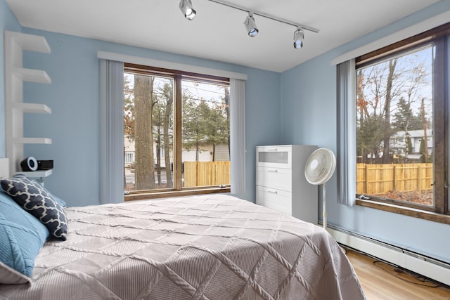 bedroom with wood finished floors and baseboard heating