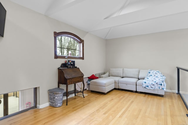 living room featuring baseboards, wood finished floors, and vaulted ceiling