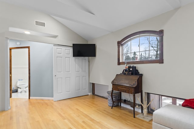 interior space featuring light wood finished floors, visible vents, and vaulted ceiling