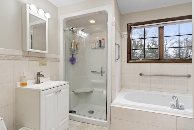 bathroom with vanity, tile walls, a bath, and a shower stall