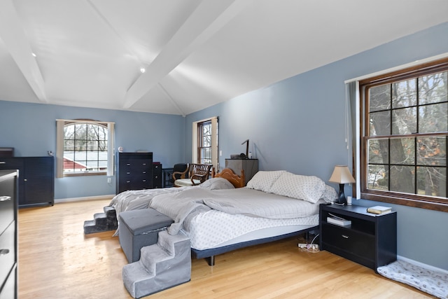 bedroom featuring vaulted ceiling with beams, baseboards, and wood finished floors