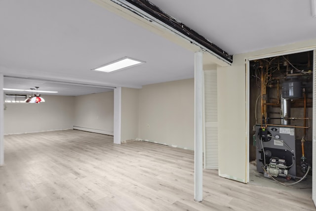 finished basement featuring a heating unit, a baseboard heating unit, and wood finished floors