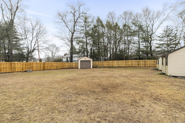 view of yard with an outdoor structure, a storage unit, a fenced backyard, and a detached garage