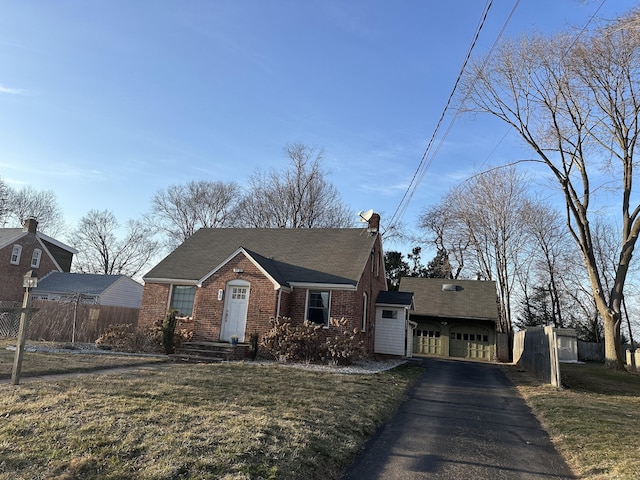 view of front facade with a front lawn, driveway, fence, an attached garage, and brick siding