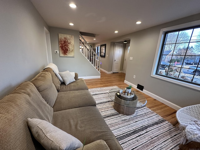 living area with recessed lighting, baseboards, stairs, and light wood finished floors