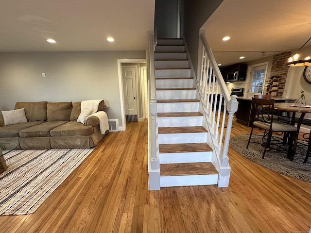 stairway with visible vents, recessed lighting, and wood finished floors