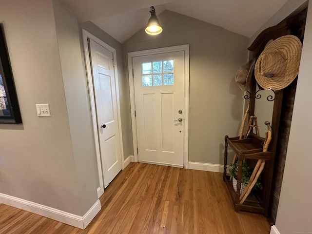 foyer entrance featuring baseboards, light wood-style floors, and lofted ceiling