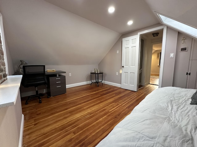 bedroom featuring vaulted ceiling with skylight, recessed lighting, wood finished floors, and baseboards