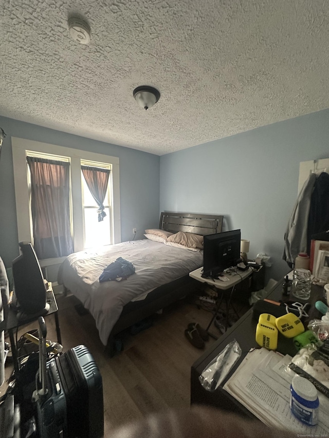 bedroom featuring wood finished floors and a textured ceiling