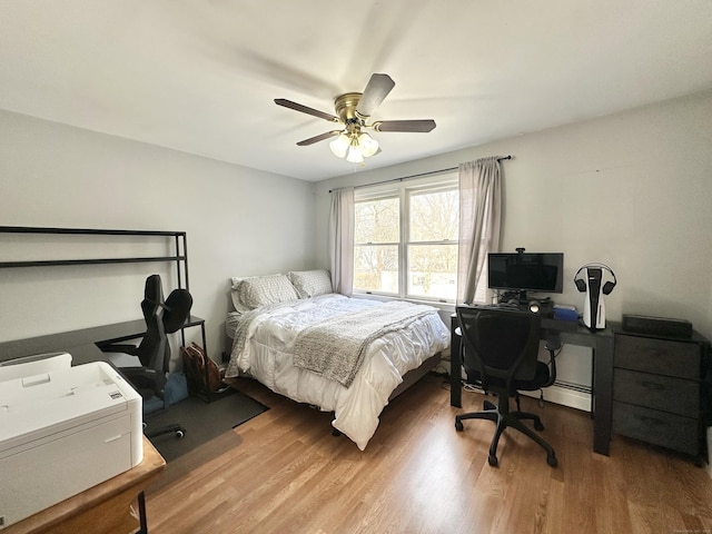 bedroom with baseboard heating, ceiling fan, and wood finished floors