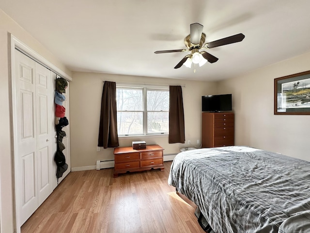 bedroom featuring baseboards, ceiling fan, light wood-style floors, a closet, and a baseboard heating unit