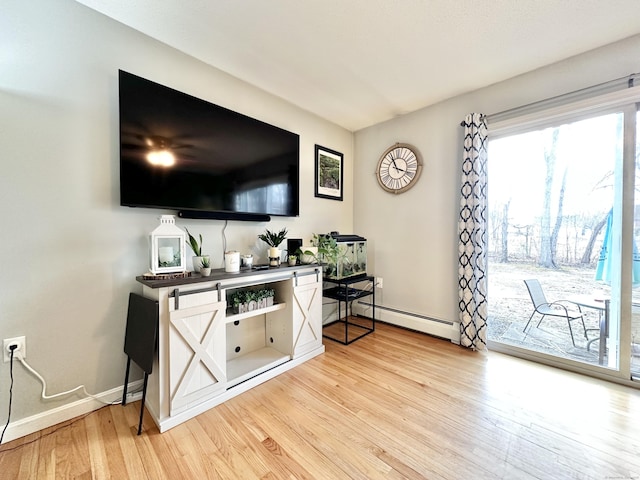 living room featuring a baseboard heating unit, light wood-style flooring, and baseboards