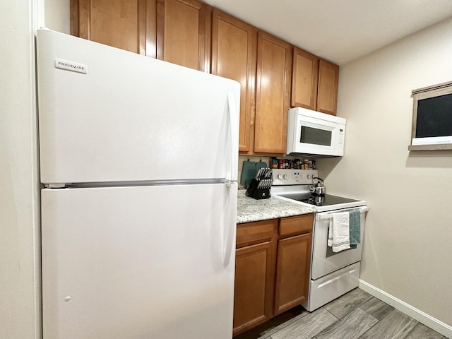 kitchen featuring light wood-type flooring, brown cabinets, white appliances, light countertops, and baseboards