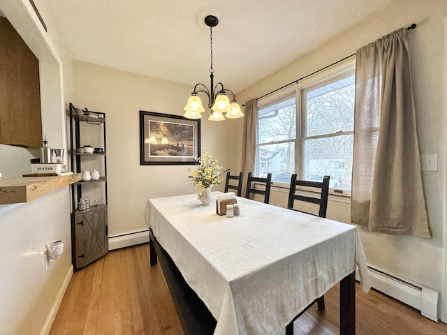 dining area featuring a chandelier, baseboard heating, and light wood-style floors