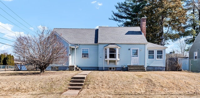 view of front of property with a front lawn, entry steps, fence, roof with shingles, and a chimney