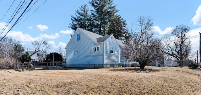 view of home's exterior featuring a yard, fence, and roof with shingles