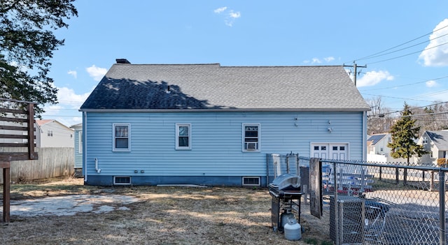 rear view of property featuring fence, a garage, and a shingled roof