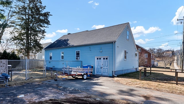 back of property featuring a gate, fence, and a shingled roof