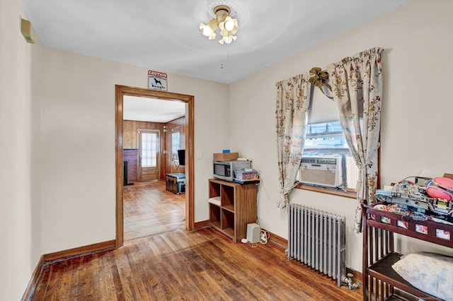 interior space with radiator, wood finished floors, baseboards, and cooling unit