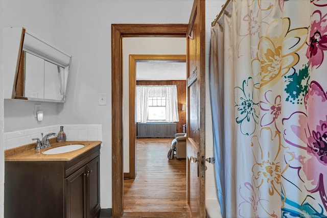 bathroom with shower / bathtub combination with curtain, radiator, wood finished floors, and vanity