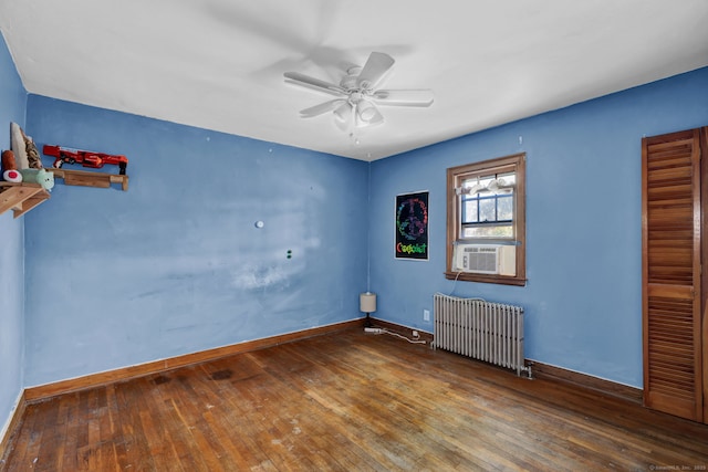 spare room with radiator, a ceiling fan, baseboards, and wood-type flooring