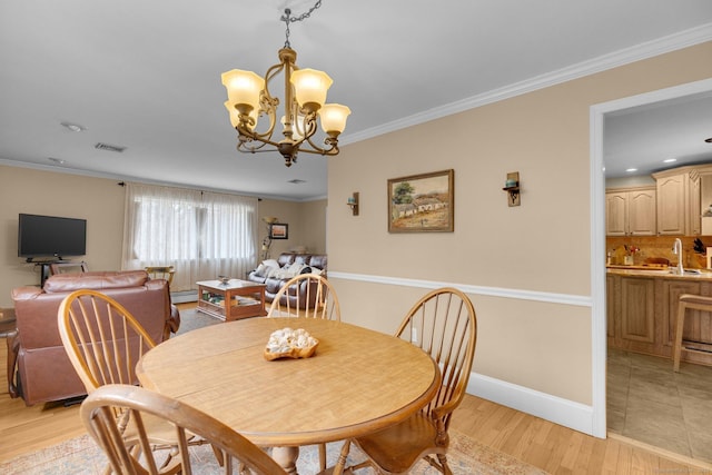 dining area with visible vents, ornamental molding, light wood-style floors, a baseboard heating unit, and a notable chandelier