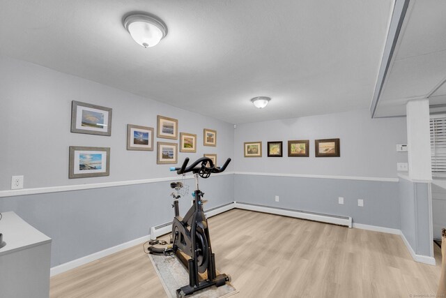 exercise room with wood finished floors, baseboards, and a baseboard radiator