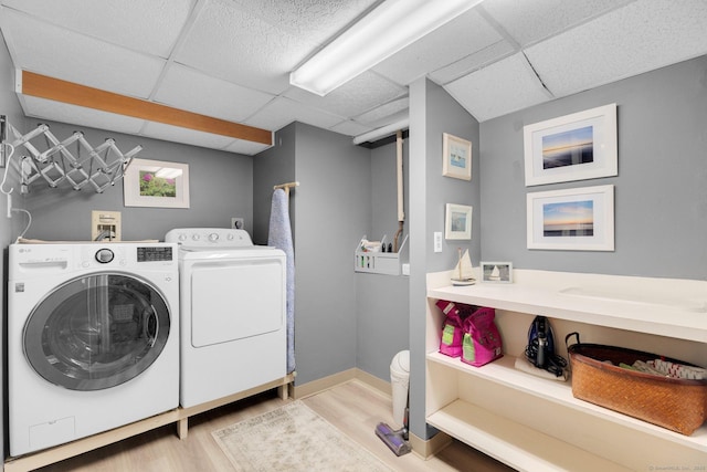 laundry area featuring light wood finished floors, laundry area, baseboards, and separate washer and dryer