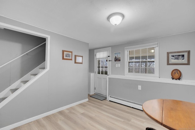 interior space with a baseboard heating unit, stairs, wood finished floors, and baseboards