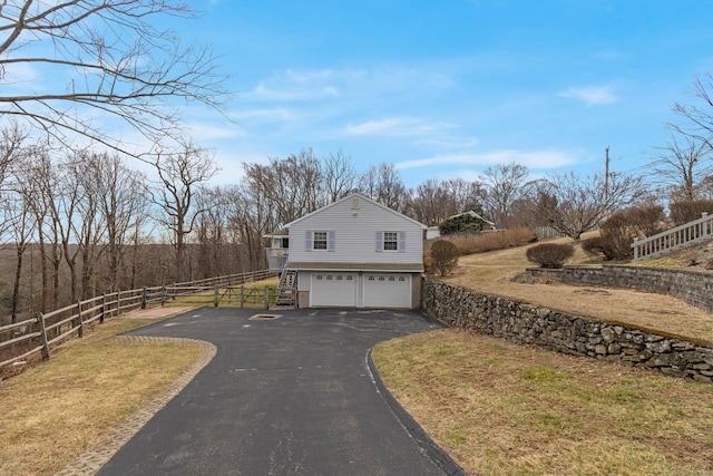 view of property exterior with a garage, driveway, and fence