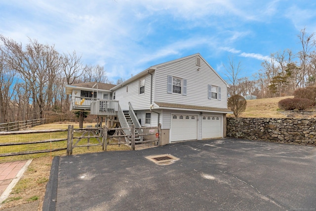 view of home's exterior with aphalt driveway, a garage, stairs, and fence