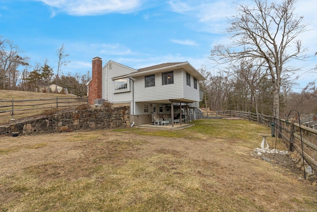 back of property featuring a lawn, a chimney, a fenced backyard, a carport, and a patio