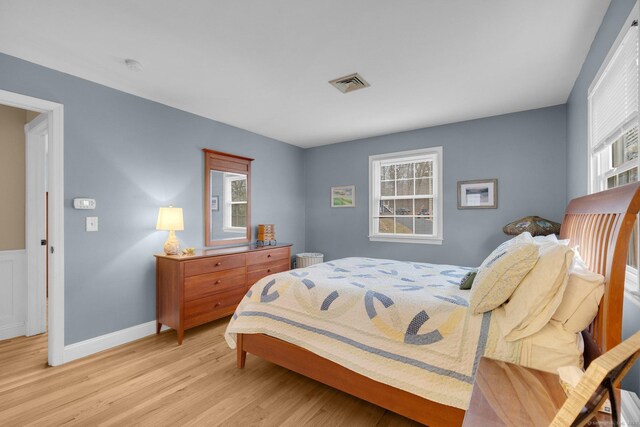 bedroom featuring multiple windows, baseboards, visible vents, and light wood finished floors