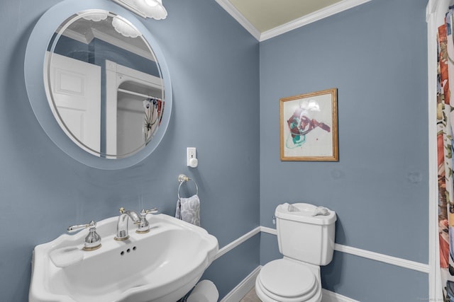 bathroom with curtained shower, crown molding, baseboards, toilet, and a sink