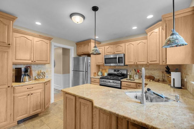 kitchen featuring light brown cabinetry, light stone countertops, stainless steel appliances, and a sink