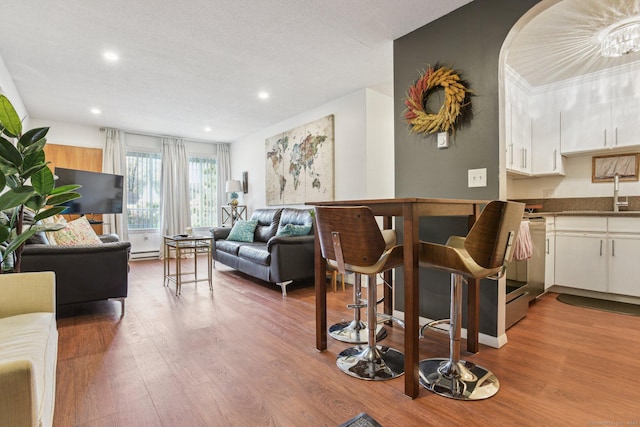 living area with recessed lighting, a baseboard heating unit, and wood finished floors