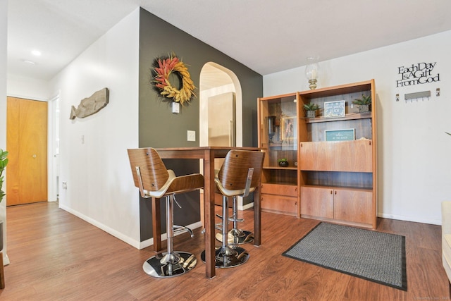 interior space with arched walkways, baseboards, and wood finished floors