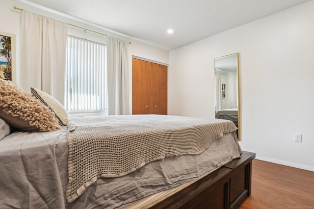 bedroom with recessed lighting, wood finished floors, baseboards, and a closet