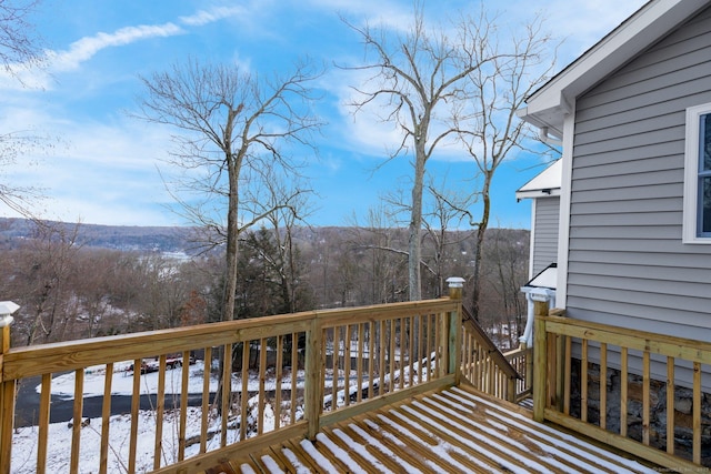 snow covered deck featuring a forest view