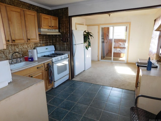 kitchen featuring white appliances, a sink, decorative backsplash, under cabinet range hood, and dark carpet