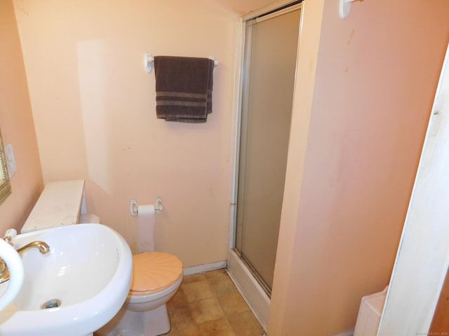 bathroom with a shower stall, toilet, and a sink