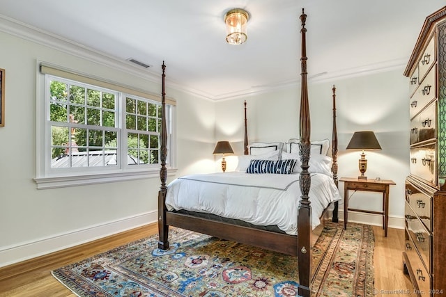 bedroom with crown molding, wood finished floors, and baseboards