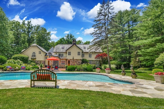 outdoor pool featuring a patio and a lawn